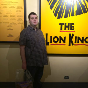 alpha school of jackson student in front of Lion King Broadway play poster
