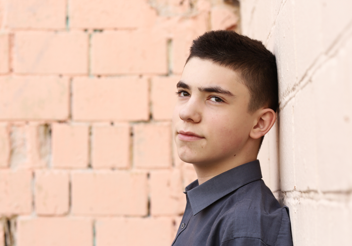 happy teenager boy wink closeup portrait on white wall background